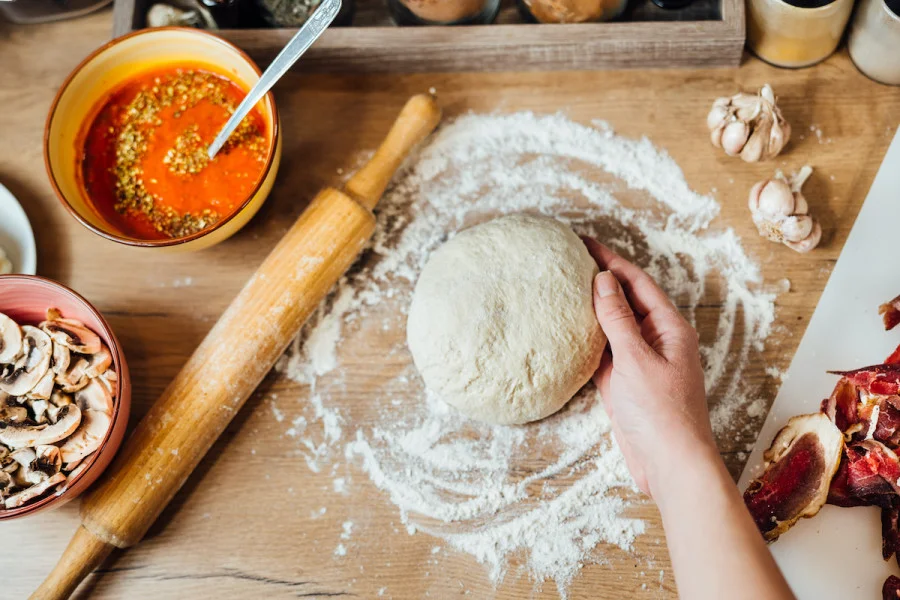 A pizza dough resting on floured surface with a rolling pin.