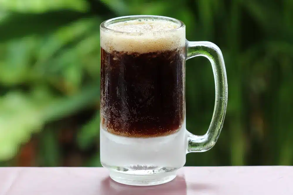 A Glass of root beer in a glass mug placed in surface